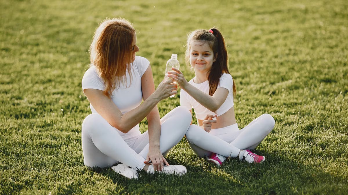 Caucasian mother and daughter in sportswear sharing a bonding moment outdoors.